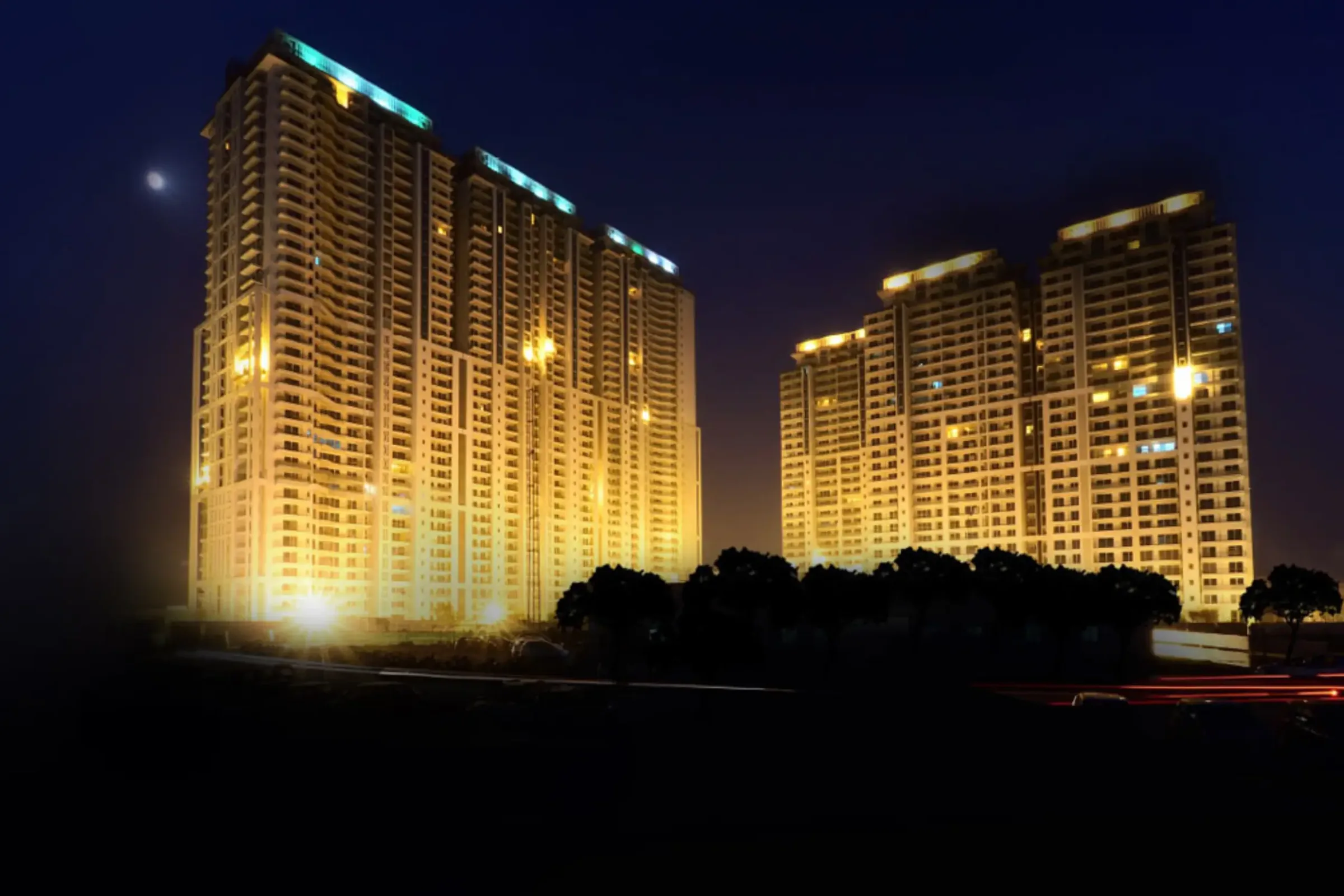 Twin illuminated high-rise towers of DLF The Crest against the night sky, Sector 54, Golf Course Road, Gurugram