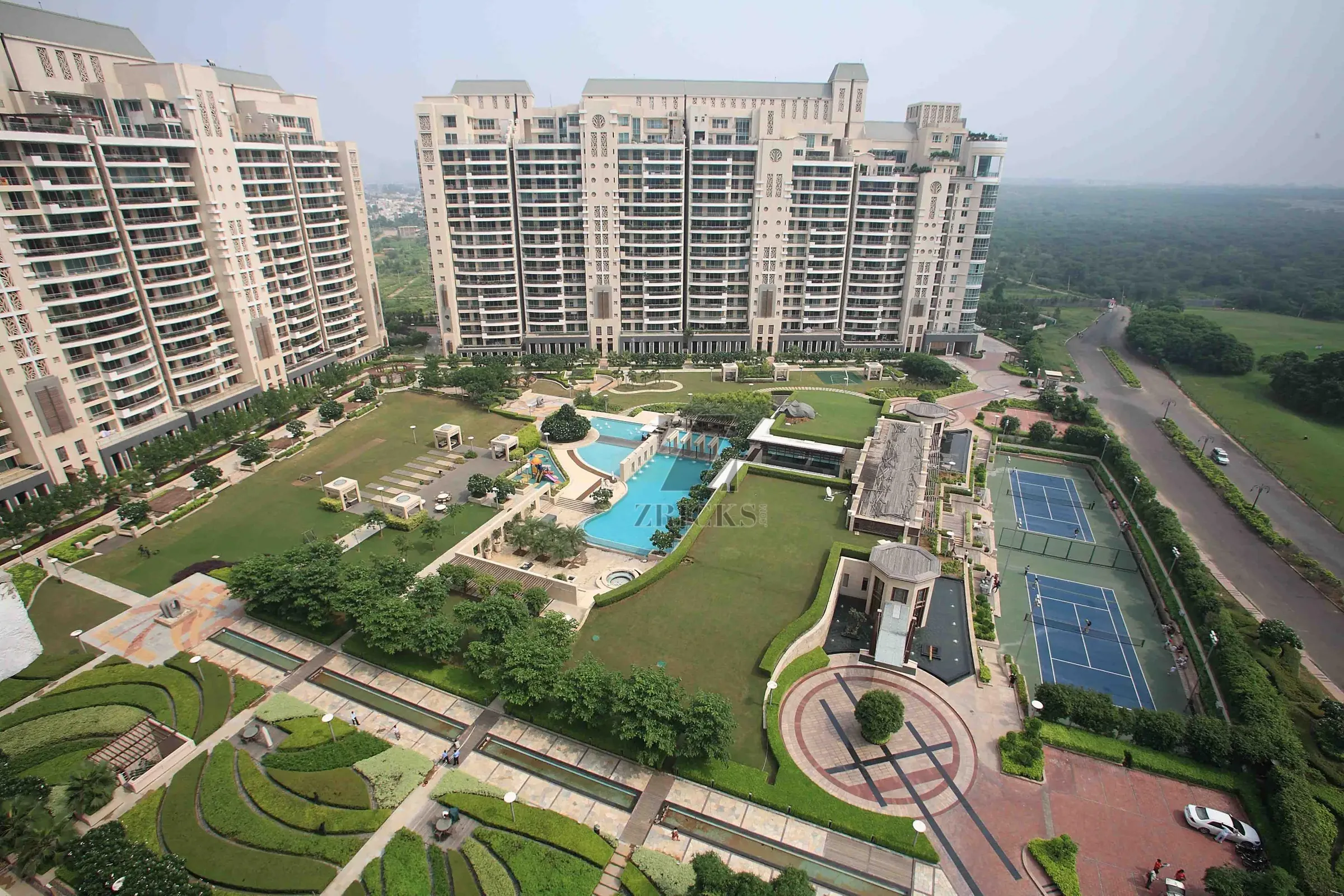 Aerial view of DLF The Magnolias towers around a pool deck and tennis courts, Sector 42, Golf Course Road, Gurugram